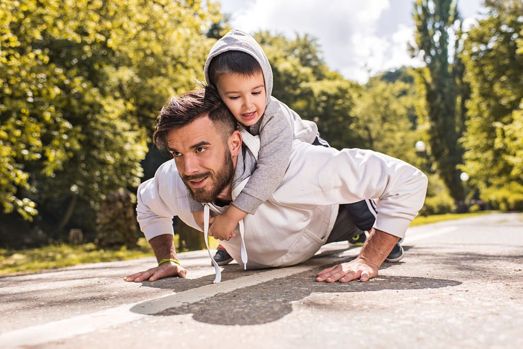 Paps menggendong anak sambil push up.