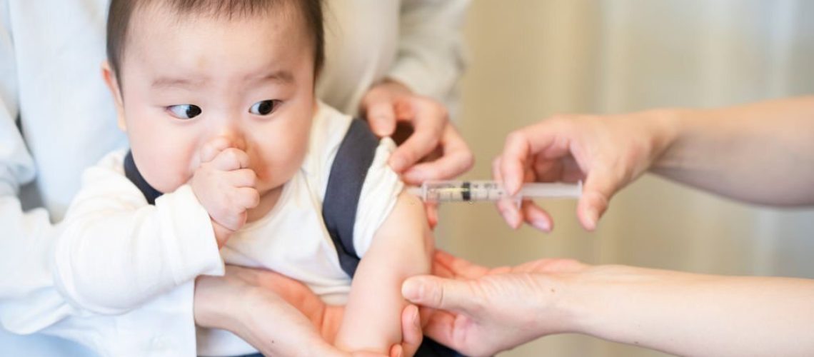 A baby who is vaccinated while being held by her mother