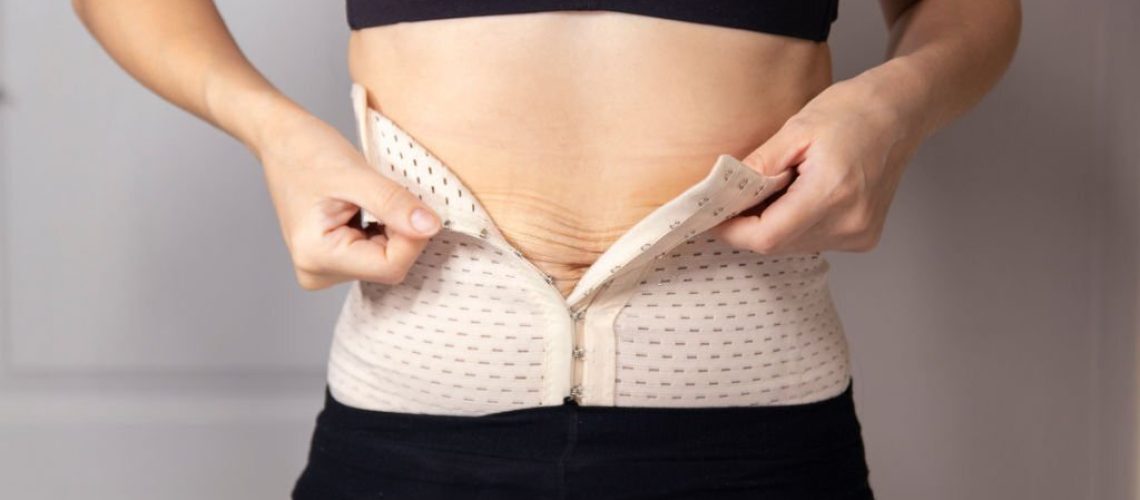 Closeup woman getting dressed, hooking on corset hooks using hands behind back, weightloss concept. A woman fastens a corset for figure correction